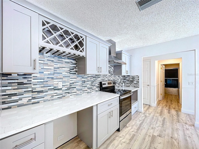 8600 Berkley Dr, Hudson, FL 34667 - kitchen with electric range, tasteful backsplash, light hardwood / wood-style floors, a textured ceiling, and wall chimney exhaust hood