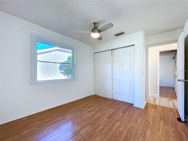 8600 Berkley Dr, Hudson, FL 34667 - unfurnished bedroom with ceiling fan, light hardwood / wood-style floors, a closet, and a textured ceiling