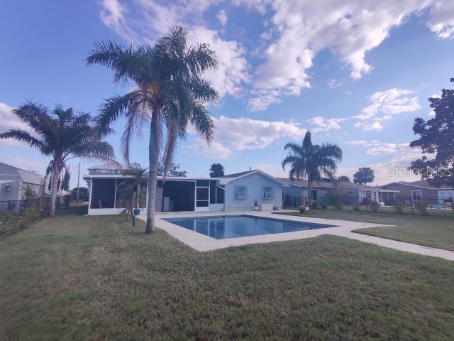 view of pool featuring a sunroom and a lawn