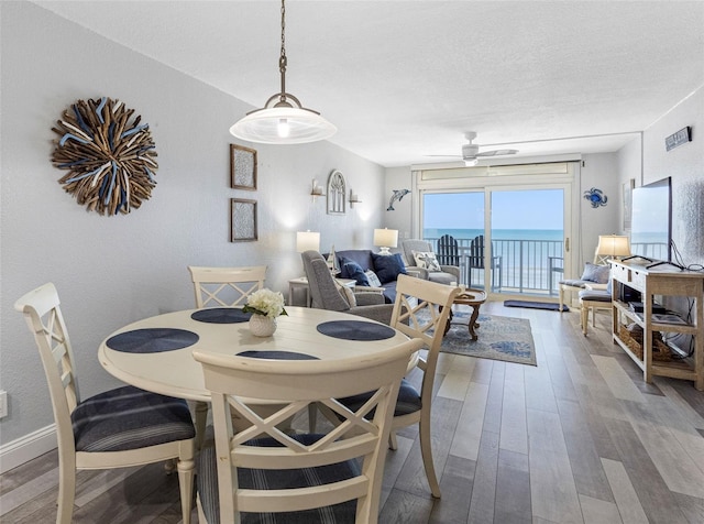 dining space with ceiling fan, a textured ceiling, and hardwood / wood-style floors