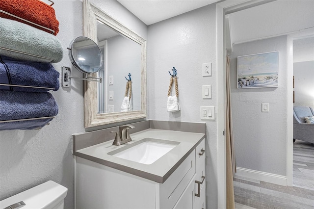 bathroom with vanity, toilet, and hardwood / wood-style floors