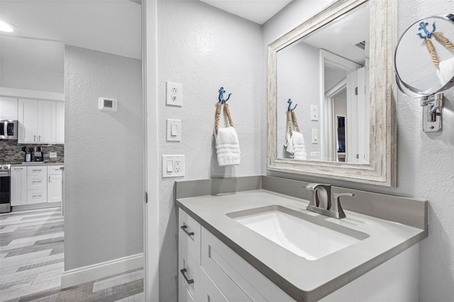 bathroom with wood-type flooring, backsplash, and vanity