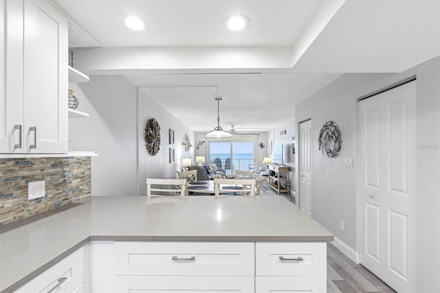 kitchen with white cabinets, pendant lighting, backsplash, hardwood / wood-style floors, and kitchen peninsula