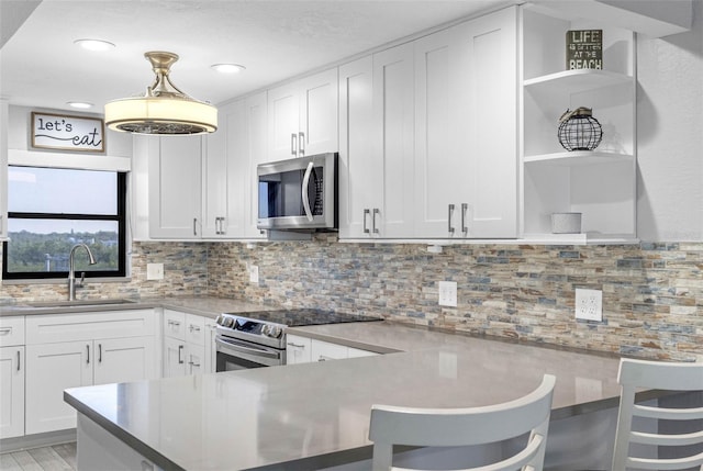 kitchen with white cabinetry, appliances with stainless steel finishes, sink, and a breakfast bar area