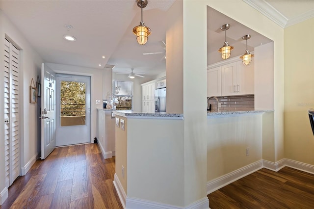 kitchen with a peninsula, white cabinetry, hanging light fixtures, light stone countertops, and stainless steel fridge