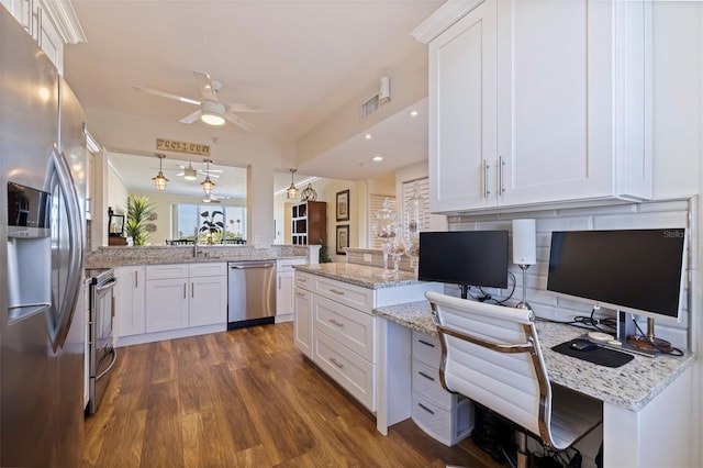 kitchen with dark wood finished floors, light stone counters, a peninsula, stainless steel appliances, and white cabinetry