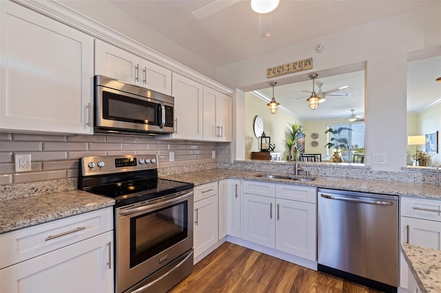 kitchen featuring decorative light fixtures, stainless steel appliances, decorative backsplash, white cabinetry, and a sink