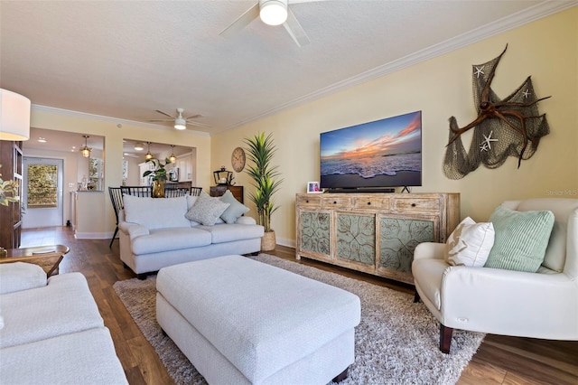 living room featuring baseboards, crown molding, a ceiling fan, and wood finished floors