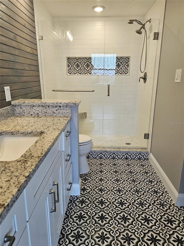 full bathroom featuring a stall shower, baseboards, vanity, and toilet