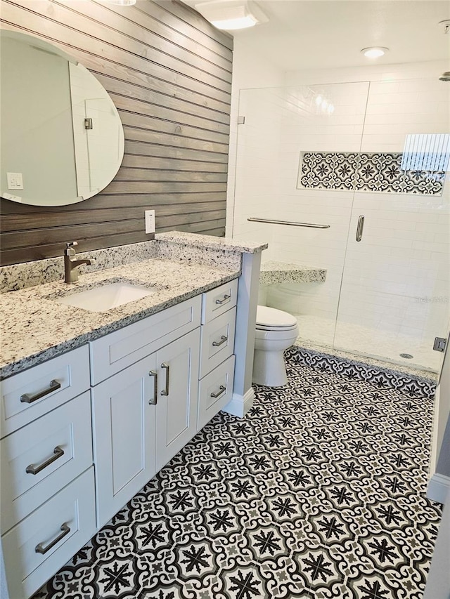 bathroom featuring a stall shower, vanity, toilet, and wooden walls