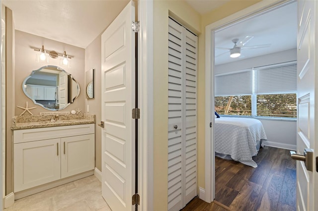 bathroom featuring a closet, wood finished floors, vanity, and baseboards