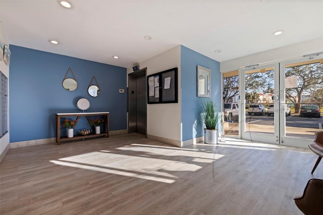 unfurnished living room with baseboards, wood finished floors, and elevator