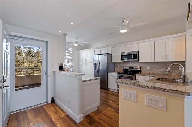 kitchen with a peninsula, ceiling fan, a sink, backsplash, and stainless steel appliances