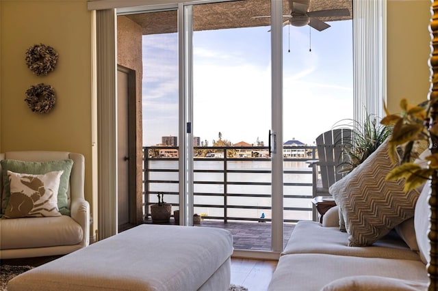 bedroom with access to outside, a water view, wood finished floors, and expansive windows