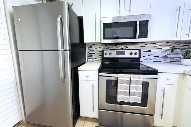 kitchen with light tile patterned flooring, appliances with stainless steel finishes, decorative backsplash, and white cabinets