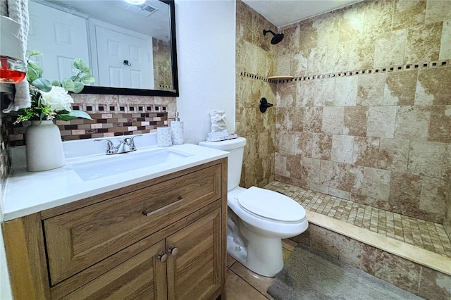 bathroom with vanity, toilet, and a tile shower