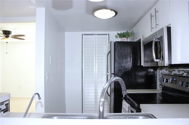 kitchen with tasteful backsplash, appliances with stainless steel finishes, white cabinets, and ceiling fan