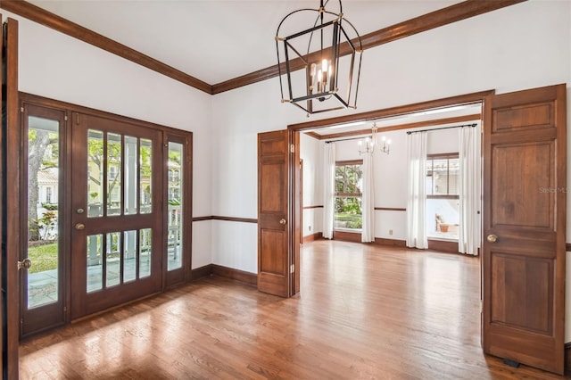 entrance foyer with ornamental molding, wood-type flooring, and a notable chandelier