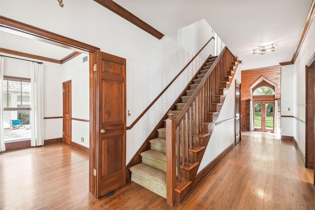 stairs featuring hardwood / wood-style flooring, crown molding, and french doors