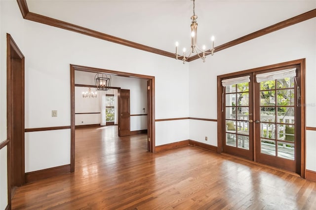 unfurnished room featuring a wealth of natural light, a notable chandelier, dark hardwood / wood-style flooring, and french doors