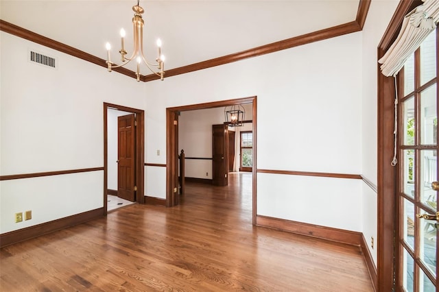 spare room featuring ornamental molding, dark hardwood / wood-style floors, a notable chandelier, and a healthy amount of sunlight