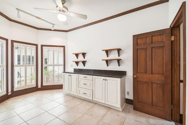 kitchen with light tile patterned floors, crown molding, ceiling fan, white cabinetry, and track lighting