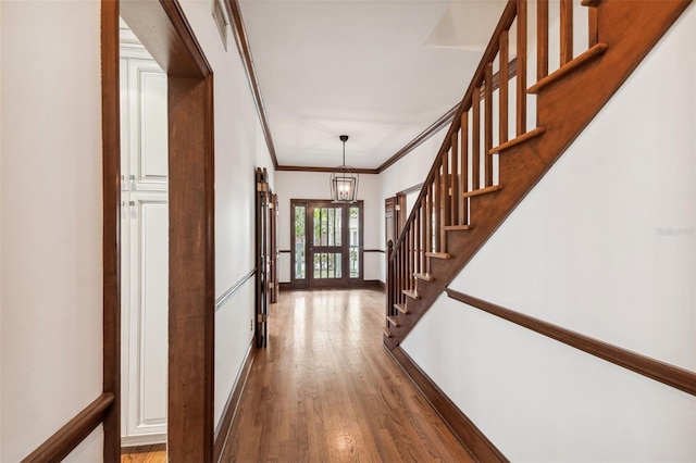 corridor featuring crown molding, hardwood / wood-style floors, and a chandelier