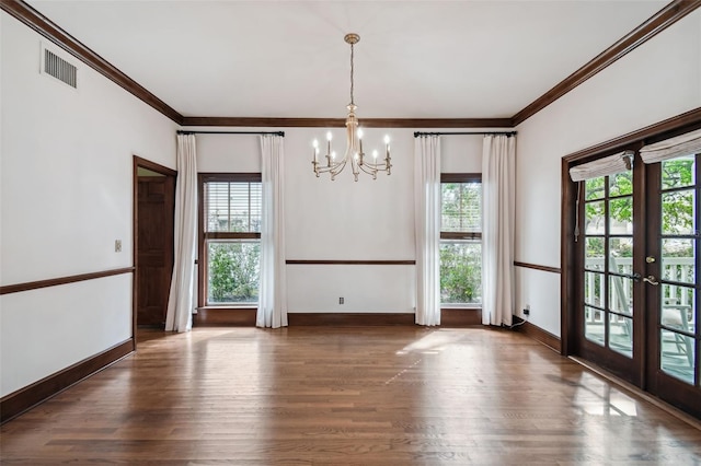 unfurnished dining area with ornamental molding, dark hardwood / wood-style floors, a notable chandelier, and french doors