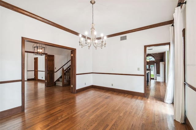 spare room with crown molding, an inviting chandelier, and dark hardwood / wood-style flooring