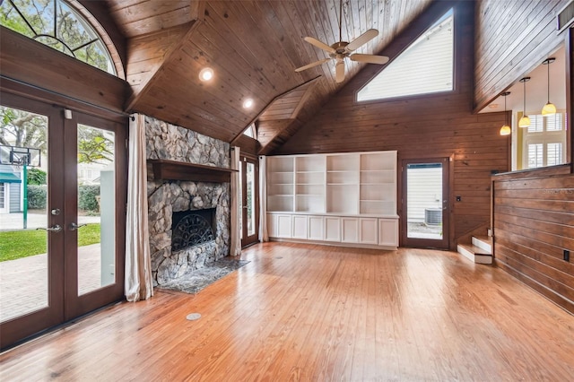 unfurnished living room featuring light hardwood / wood-style floors, french doors, and wood walls