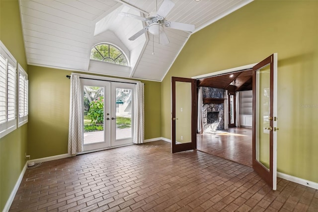 doorway to outside featuring a fireplace, high vaulted ceiling, french doors, and ceiling fan