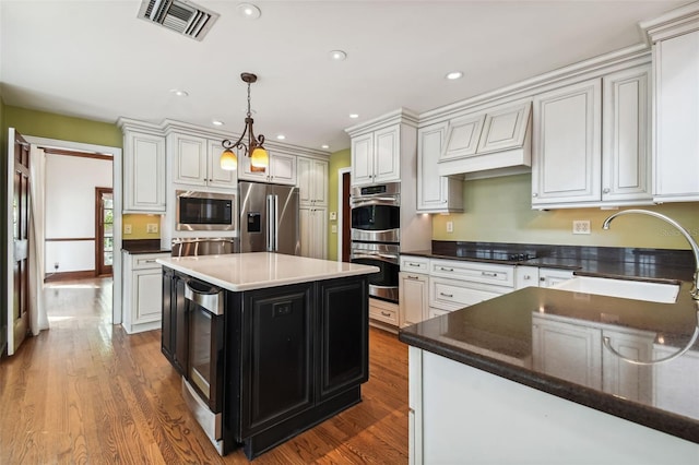 kitchen with a kitchen island, pendant lighting, sink, white cabinets, and stainless steel appliances