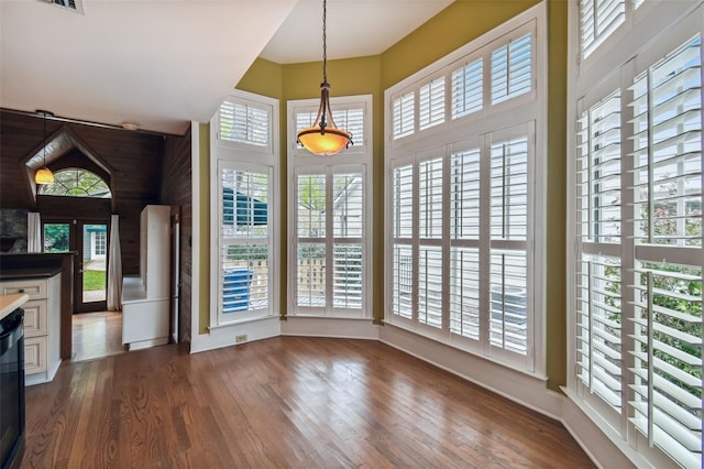 interior space with pendant lighting, white cabinetry, a healthy amount of sunlight, and dark hardwood / wood-style flooring