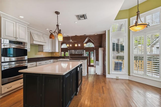 kitchen featuring a wealth of natural light, pendant lighting, white cabinets, and double oven