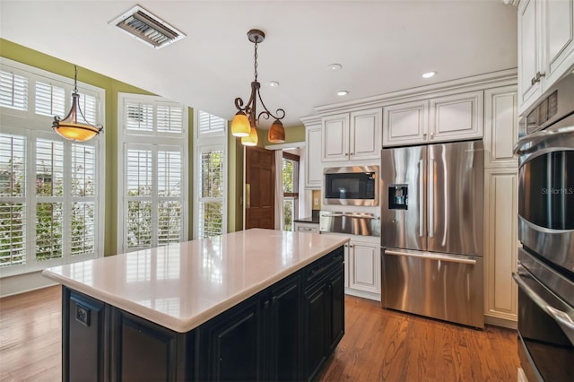 kitchen with white cabinetry, decorative light fixtures, a center island, dark hardwood / wood-style floors, and stainless steel appliances