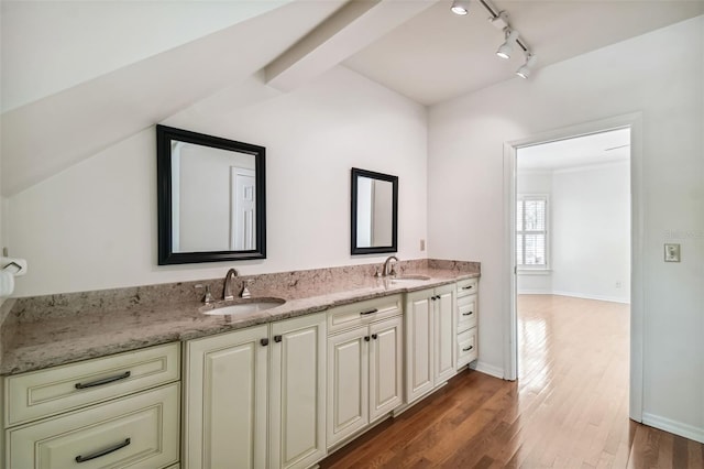 bathroom with wood-type flooring, vaulted ceiling, and vanity