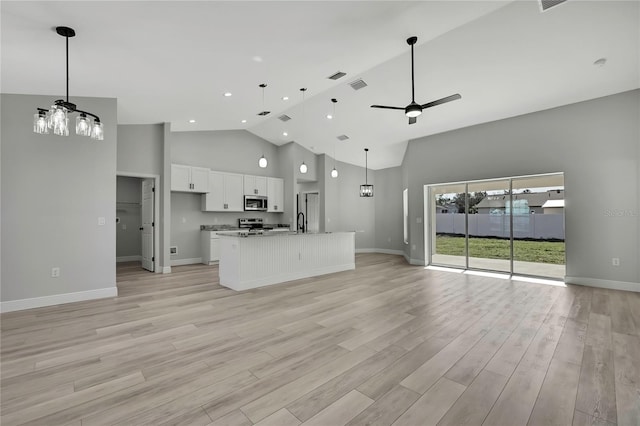 kitchen with light wood-style flooring, appliances with stainless steel finishes, a ceiling fan, open floor plan, and white cabinets