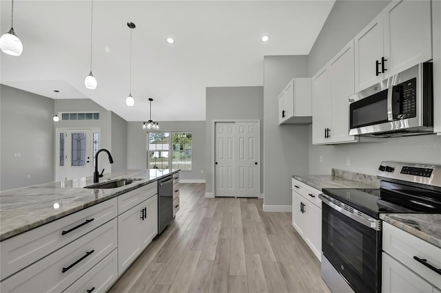 kitchen featuring light stone counters, stainless steel appliances, light wood-style floors, white cabinetry, and a sink