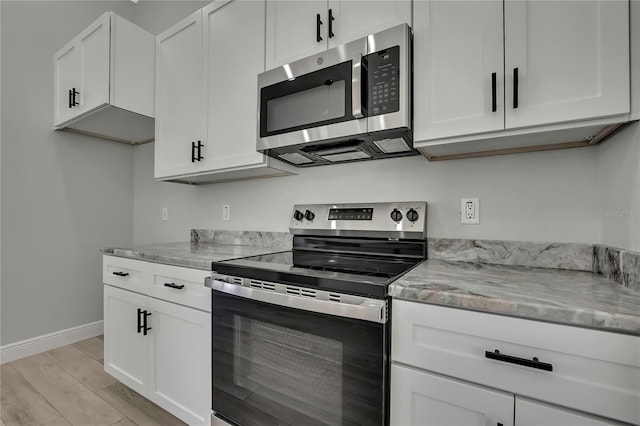 kitchen with light stone countertops, white cabinetry, and appliances with stainless steel finishes