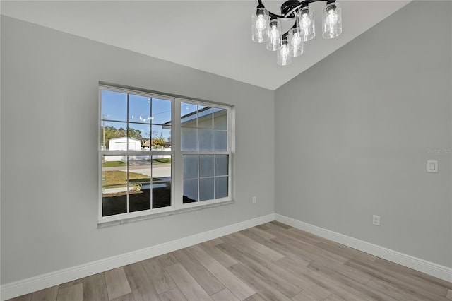 spare room with light wood finished floors, baseboards, and vaulted ceiling