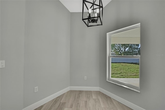 unfurnished dining area with a chandelier, baseboards, and wood finished floors