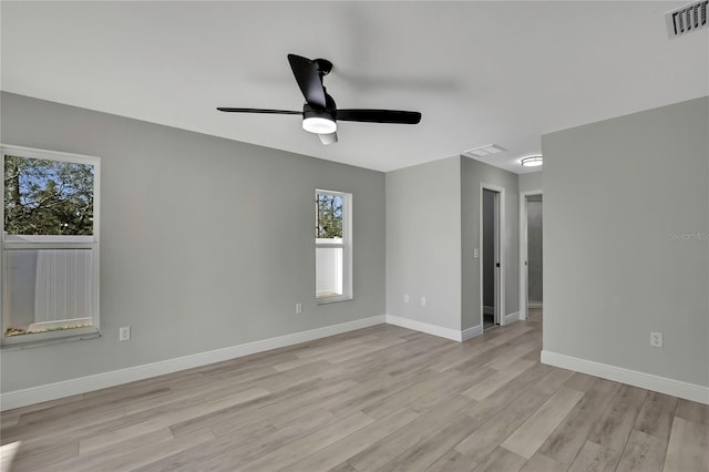 spare room with ceiling fan, light wood finished floors, visible vents, and baseboards