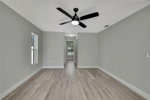 unfurnished room featuring light wood finished floors, a ceiling fan, visible vents, and baseboards