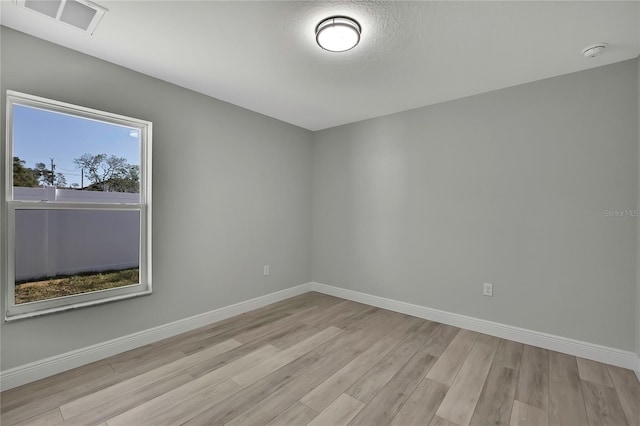 unfurnished room with baseboards, visible vents, and light wood finished floors