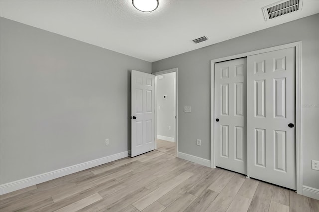 unfurnished bedroom with light wood finished floors, visible vents, and baseboards