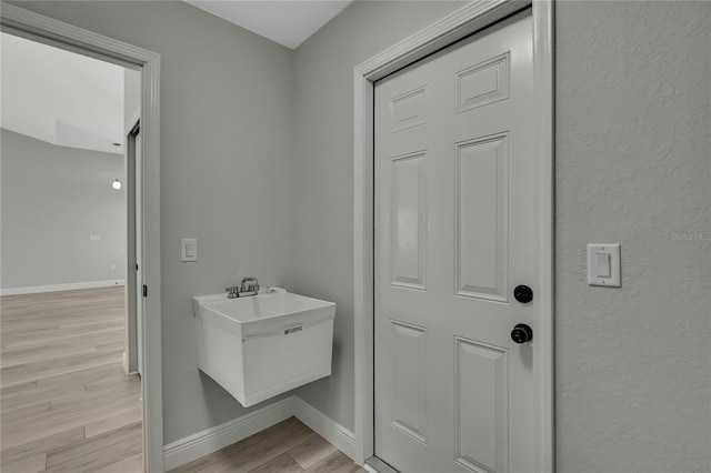 interior space with a sink, wood finished floors, and baseboards