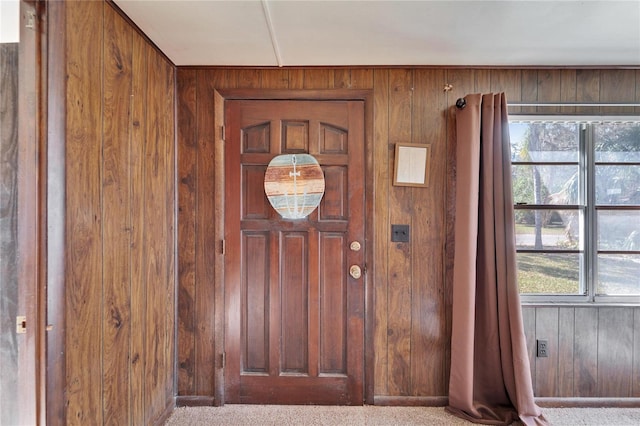 carpeted entryway featuring wood walls