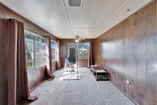 unfurnished room featuring ceiling fan, light carpet, and wood walls