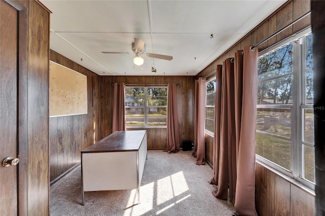 office space featuring light colored carpet, ceiling fan, and wood walls