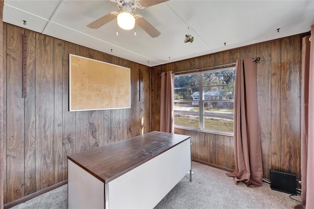 unfurnished office with light colored carpet, ceiling fan, and wood walls